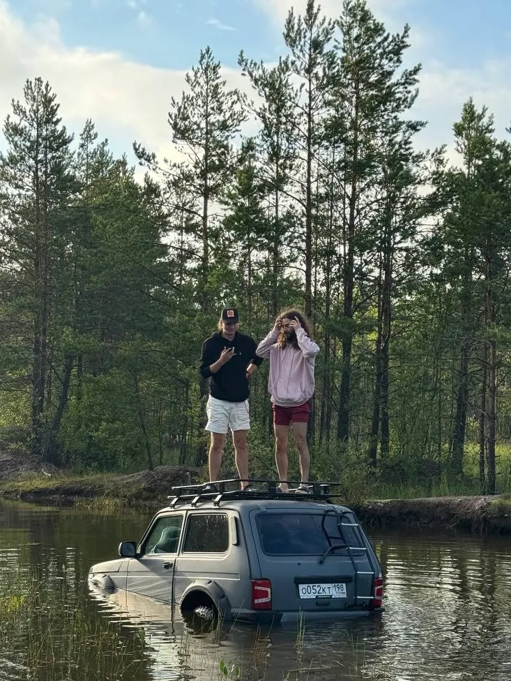 Two RealAI teammates standing on the roof of a car stuck in a lake
